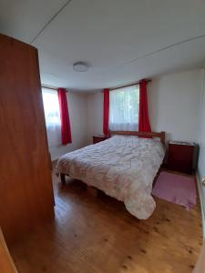 1 dormitorio con 1 cama y cortinas rojas en Cabañas Emanuel, en Chonchi