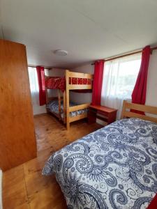 a bedroom with a bed and two bunk beds at Cabañas Emanuel in Chonchi