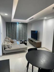 ein Wohnzimmer mit einem Sofa, einem Tisch und einem TV in der Unterkunft Apartment with Modern Amenities in Muscat
