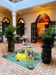 um átrio com uma fonte, uma mesa e vasos de plantas em Riad Bamaga em Marraquexe