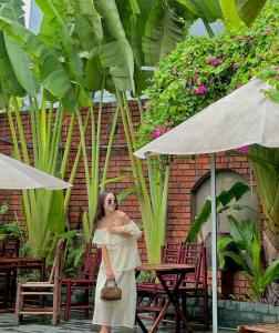 una mujer con un vestido de pie bajo un paraguas en La Belle Vie Tam Coc Homestay, en Ninh Binh
