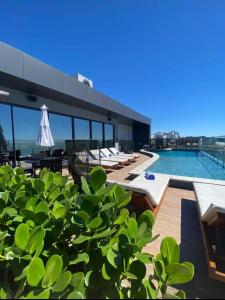 a building with a swimming pool and a patio with chairs at Não tem vagas mais , o aplicativo tá com bugue e está deixando fazer reserva, porém não tem mais disponibilidade para mais nem um dia nem ano in Itajaí