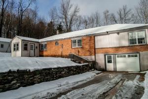 ein Backsteinhaus mit Garage im Schnee in der Unterkunft Birch House: Cozy Cabin 5 min from Okemo in Ludlow