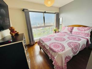 Un dormitorio con una cama con un osito de peluche junto a una ventana en Habitaciones privadas con vista al parque castilla en Lima