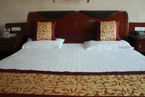 duże łóżko z dwoma poduszkami na górze w obiekcie Taizhou Taishan Business Hotel w mieście Taizhou