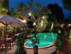 a pool at night with tables and umbrellas at La Belle Vie Tam Coc Homestay in Ninh Binh