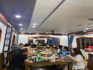 a group of people sitting at a table eating food at La Belle Vie Tam Coc Homestay in Ninh Binh
