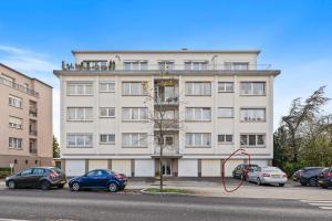 a large white building with cars parked in a parking lot at Charming 1BR Apt w/ Terrace & 5 min Drive to City in Luxembourg