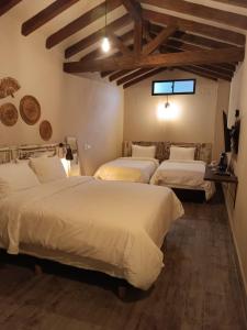 drie bedden in een kamer met houten plafonds bij Valerio Hotel Boutique in Marinilla