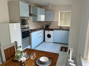 cocina con armarios azules y mesa de madera en One-Bedroom Flat with Parking and Garden, en Birmingham