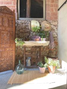 une table avec des plantes en pot à côté d'un mur de pierre dans l'établissement L'ESTABLE DE CAN TABERNER, à Bigues i Riells
