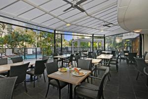 a dining room with tables and chairs and windows at Sovereign on the Gold Coast in Gold Coast