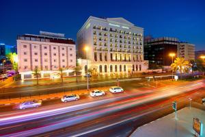 une ville la nuit avec des voitures dans une rue animée dans l'établissement Royal Ascot Hotel, à Dubaï