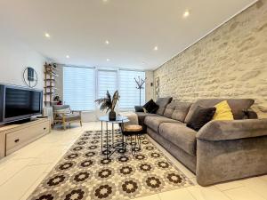 a living room with a couch and a tv at La sapinière, duplex de charme in Hermanville-sur-Mer