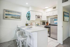 een keuken met witte kasten en een aanrecht met krukken bij Beach Quarters #6 in St Petersburg