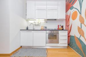 een keuken met witte kasten en een wastafel bij Casa Navigli - Cozy Apartment in Milaan