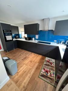 a kitchen with black cabinets and a wooden floor at En-suites and Rooms Near Wembley Stadium in London
