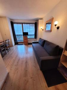 een woonkamer met een bank en houten vloeren bij Résidence Plan Soleil - 2 Pièces pour 4 Personnes 24 in Valloire