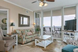 a living room with a couch and a television and a balcony at 4 Bedroom Luxury High Rise Corner Condo with 2 Balconies, Heated Pool, Direct Beach Access in Gulf Shores