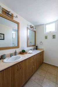 La salle de bains est pourvue de 2 lavabos et d'un grand miroir. dans l'établissement Adjust Your Latitude - Amazing Sea & Marina Views, à Fajardo