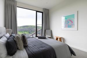 a bedroom with a bed and a large window at Topdeck at Snelling Beach in Stokes Bay