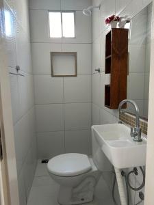 a white bathroom with a toilet and a sink at Chalé Betel in Galinhos