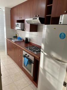 eine Küche mit Holzschränken und einem weißen Kühlschrank in der Unterkunft ACOGEDOR DEPARTAMENTO DE TRES DORMITORIO in Santiago