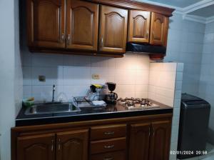 una cocina con armarios de madera y fregadero en Bonito apartamento en Cartagena con garaje gratuito, en Cartagena de Indias