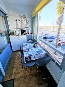 a dining room with a table and a view of a boat at Résidence LES TERRASSES DU PORT - 2 Pièces pour 4 Personnes 04 in Port Leucate