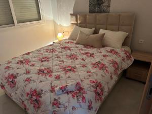 una camera con un letto e un piumone floreale di le Lys apprt Oujda a Oujda