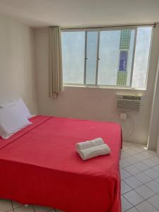 a bedroom with a red bed with a towel on it at Hotel América Praia in Recife