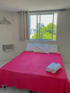 a bedroom with a pink bed with two towels on it at Hotel América Praia in Recife