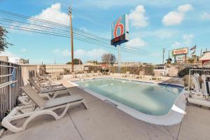 a pool with chaise lounge chairs and a swimming pool at Motel 6-Austin, TX - South - Airport in Austin