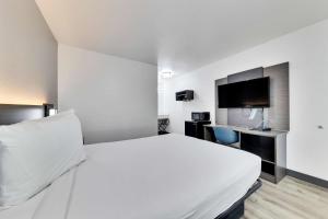 a hotel room with a white bed and a flat screen tv at Motel 6-Austin, TX - South - Airport in Austin