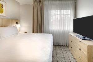 um quarto de hotel com uma cama e uma televisão de ecrã plano em Sonesta Simply Suites Miami Airport Doral em Miami