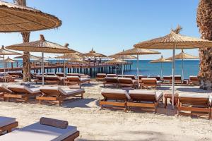 a beach with chairs and umbrellas and the ocean at Cullinan Belek in Belek