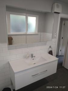 uma casa de banho branca com um lavatório e um espelho em Cabin style / sleepout em Christchurch