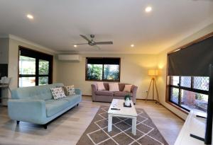 a living room with two couches and a flat screen tv at 12 Wilfred Street in Bargara