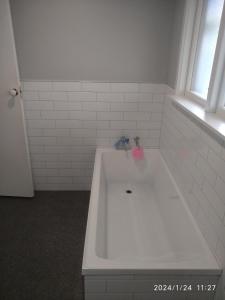 uma banheira branca na casa de banho com uma janela em Cabin style / sleepout em Christchurch
