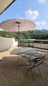 a table and a chair with an umbrella on a balcony at Résidence Les Glovettes - Studio pour 4 Personnes 164 in Villard-de-Lans