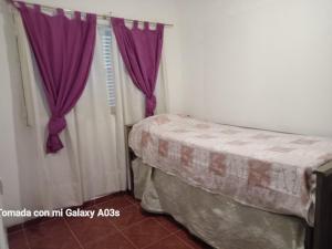 una camera con letto e tende viola di Residencia Marta a Colonia Caroya