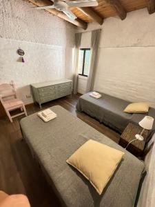 Cette chambre comprend 2 lits et une chaise. dans l'établissement Alojamiento La Casita de Lunlunta, Maipú, Mendoza, à Maipú