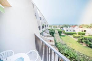 a balcony with white chairs and a yard at SUNLIGHT HORIZON* Parking * Terrasse * Vue Mer * WIFI *Famille in La Grande Motte
