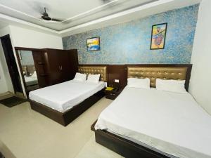 um quarto com 2 camas e uma parede azul em The Boston Rooms em Agra