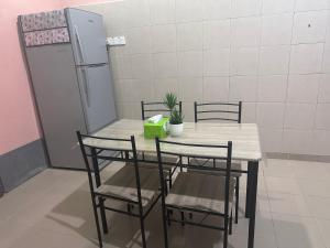 a table with chairs and a refrigerator in a room at Raudah Homestay in Kota Bharu