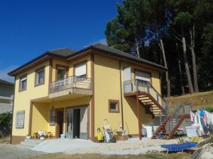 a yellow house with a balcony and a staircase at Casa Do Marabillas in Portomarin