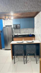 uma cozinha com uma mesa, 2 cadeiras e um frigorífico em Maresia 7B em Salvador