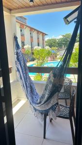 a hammock on a balcony with a view of a pool at Maresia 7B in Salvador
