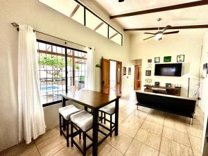 a dining room with a table and chairs and a television at Oasis Arenal Villa Pool & Arenal Volcano View in Fortuna
