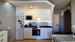 La cuisine est équipée de placards blancs et d'un réfrigérateur blanc. dans l'établissement BENALBEACH SEA VIEW 2BDR Apartment with Water Park, à Benalmádena